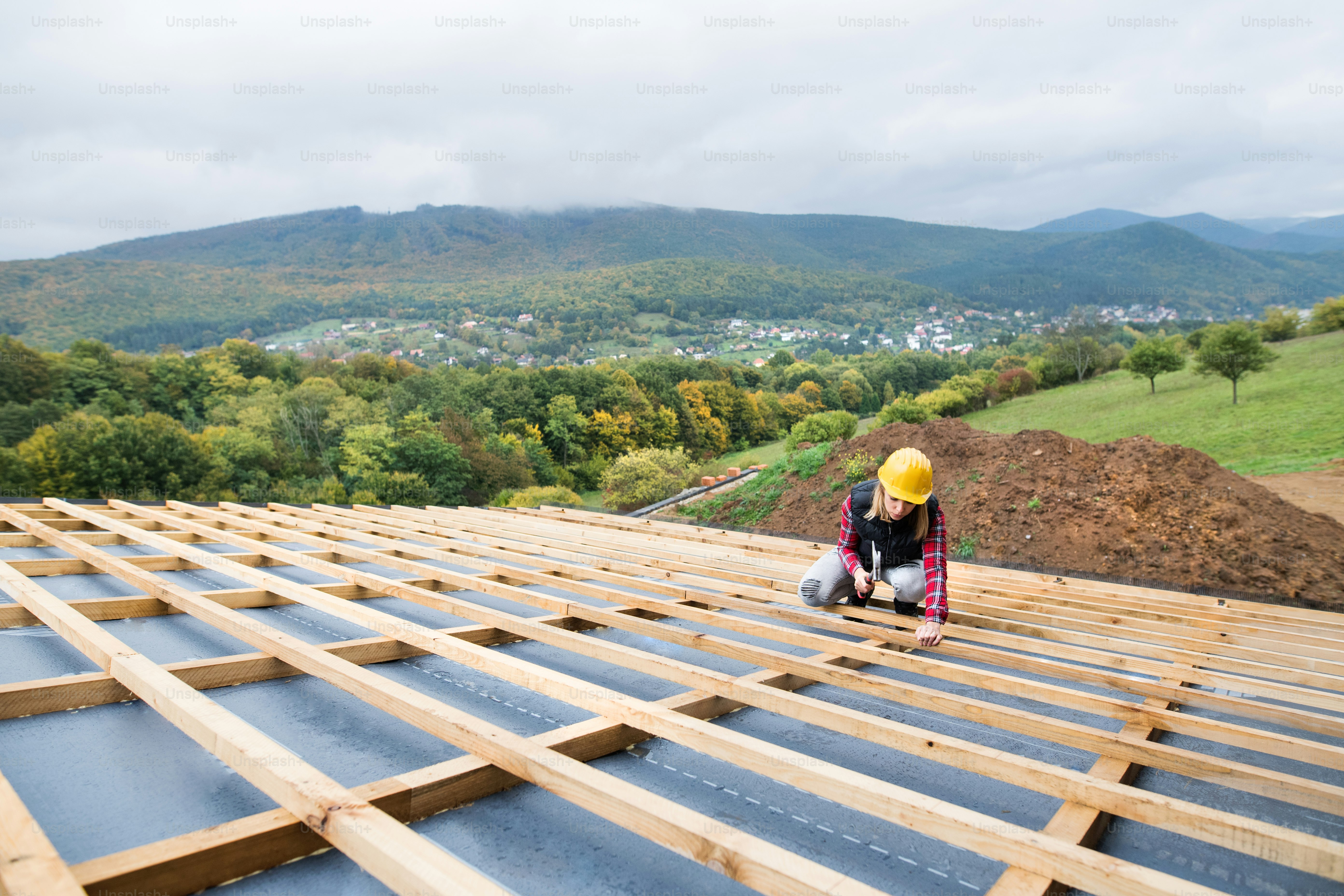 Female worker on the building site. Young woman working as a roofer. House construction